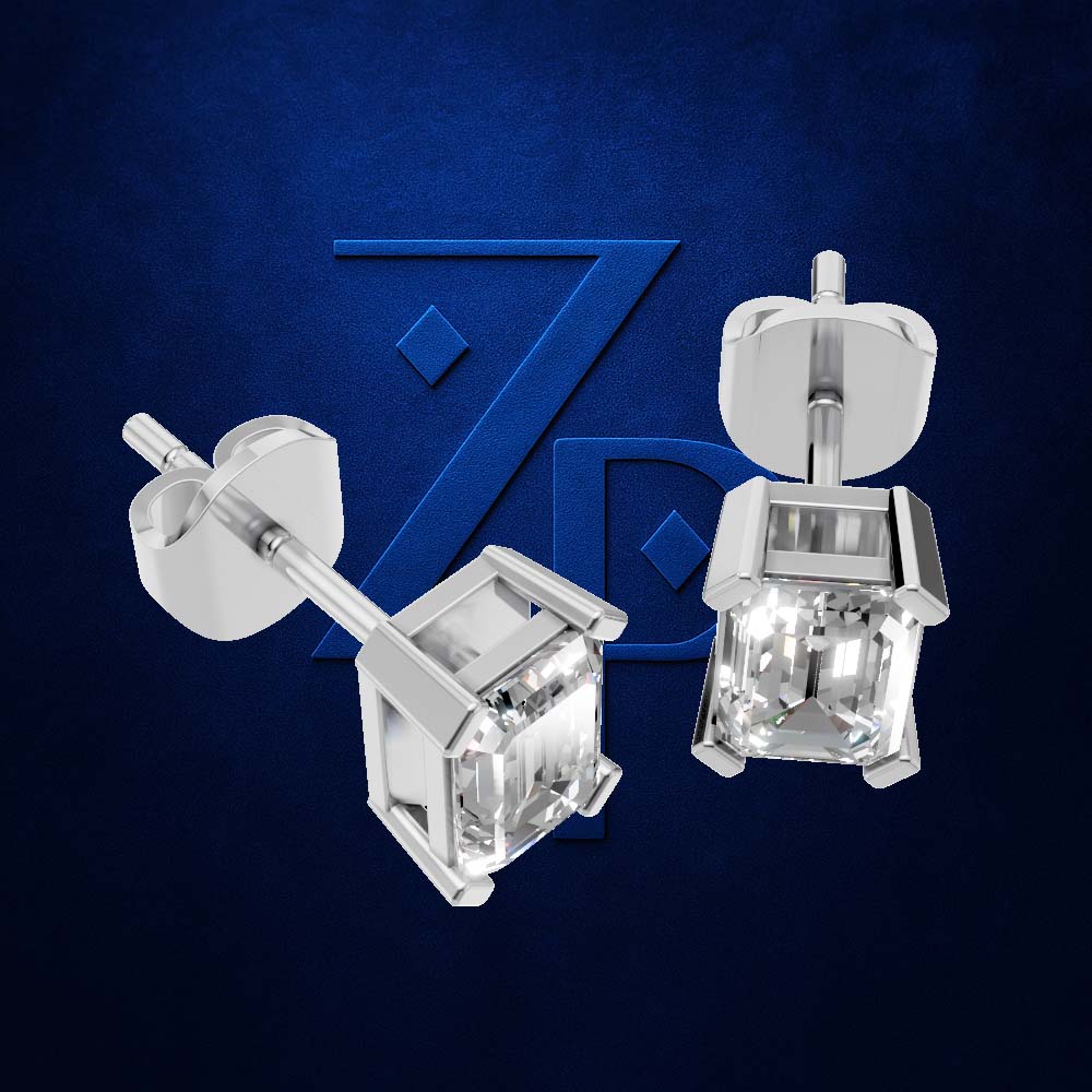 A pair of silver-toned stud earrings with square-cut clear gemstones, shown from front and side angles against a textured dark blue background with a subtle stylized logo.