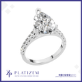 A pear-cut diamond solitaire ring in a silver-colored setting, shown on a white background with a blue border and the Platizem brand logo at the bottom.