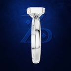 A polished silver-toned diamond engagement ring set in a high-profile round bezel, displayed vertically against a textured dark blue background with a subtle blue geometric logo.