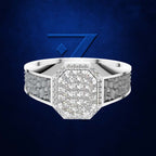 A silver-toned octagonal ring with a pavé diamond center and textured beaded sides, shown against a dark blue textured background with a blue geometric logo behind it.
