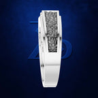 A white gold or platinum ring featuring a central channel filled with small gray stones, shown on a textured dark blue background with a subtle blue geometric logo behind it.