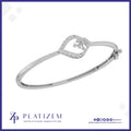 A silver-toned hinged bangle bracelet with a decorative heart-shaped frame set with small clear stones and a central floral motif, shown on a white background with the brand name PLATIZEM at the bottom.
